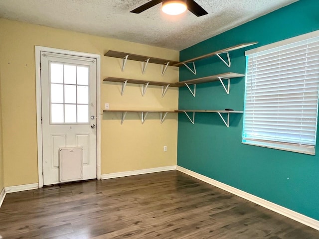 interior space with a textured ceiling, dark wood finished floors, and baseboards