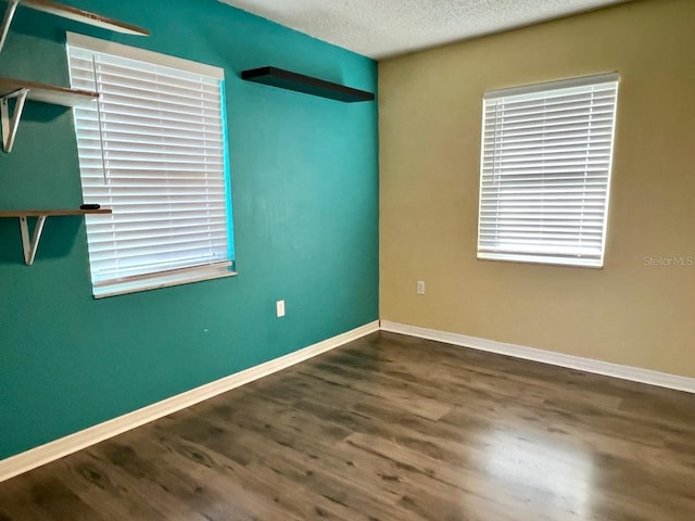 spare room with baseboards, a textured ceiling, and wood finished floors