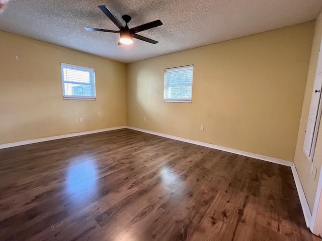 empty room with dark wood finished floors, a textured ceiling, baseboards, and ceiling fan