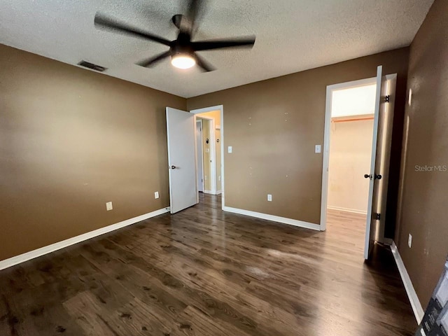 unfurnished bedroom with a textured ceiling, dark wood-type flooring, and visible vents