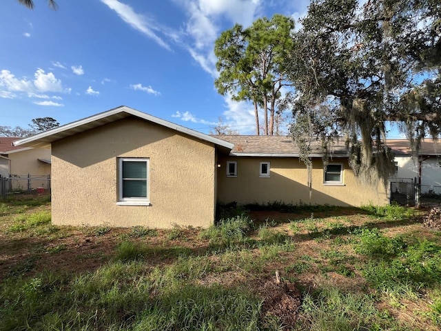 view of side of property with fence and stucco siding