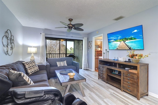 living area with light wood-style floors, a textured ceiling, visible vents, and a ceiling fan