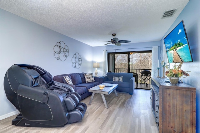 living area with a textured ceiling, light wood finished floors, visible vents, and a ceiling fan