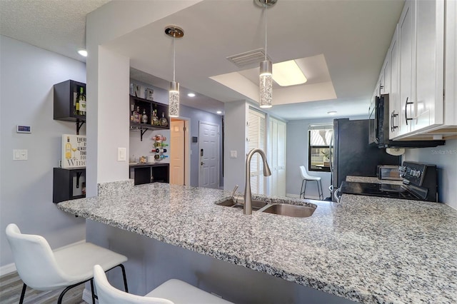 kitchen with a peninsula, electric range, a sink, visible vents, and white cabinets