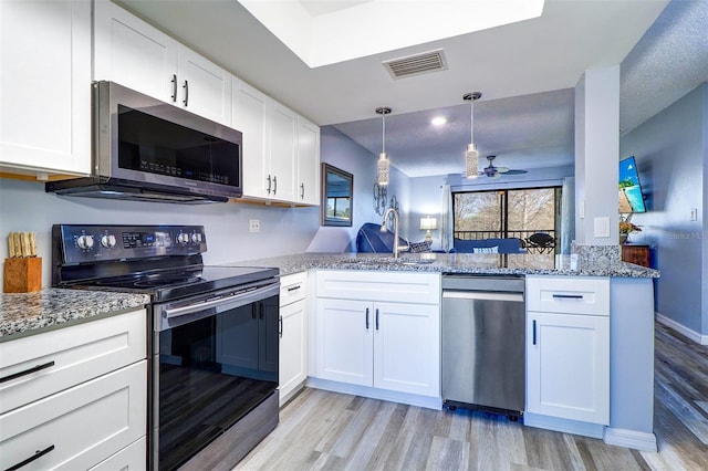 kitchen with visible vents, appliances with stainless steel finishes, white cabinets, a sink, and a peninsula