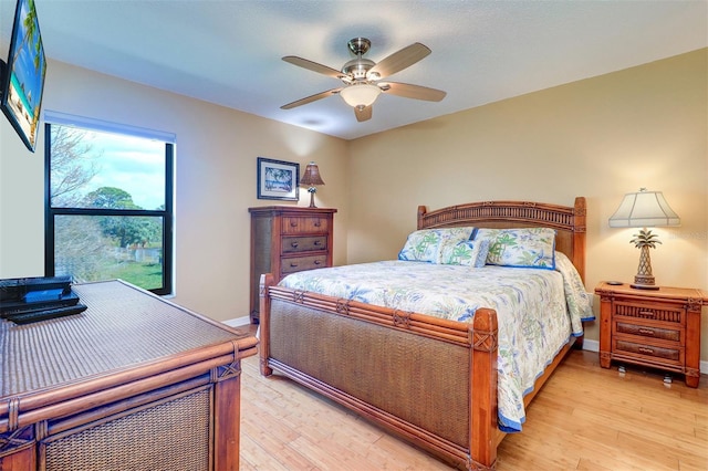 bedroom with ceiling fan, light wood finished floors, and baseboards