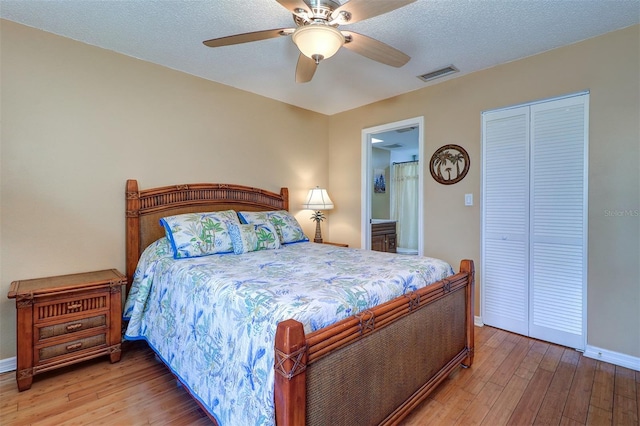 bedroom with a ceiling fan, visible vents, baseboards, a closet, and wood-type flooring