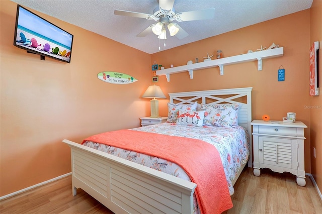 bedroom with a ceiling fan, a textured ceiling, baseboards, and wood finished floors