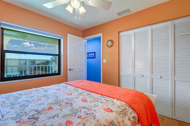 bedroom with ceiling fan, a textured ceiling, visible vents, and a closet