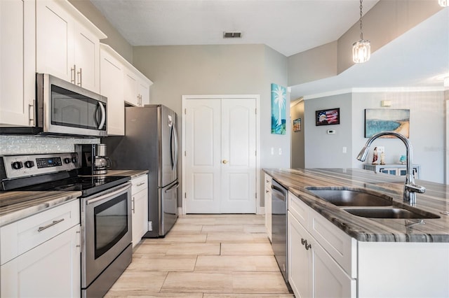 29312 Marker Loop, San Antonio, FL 33576 - kitchen with appliances with stainless steel finishes, a sink, white cabinets, a kitchen island with sink, and light wood-style flooring