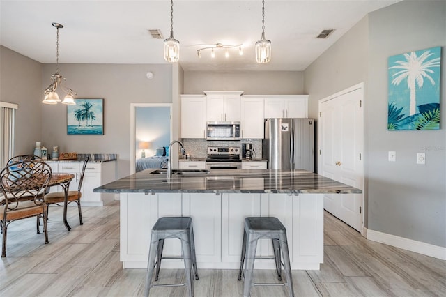 29312 Marker Loop, San Antonio, FL 33576 - kitchen featuring stainless steel appliances, a sink, tasteful backsplash, a center island with sink, and light wood finished floors