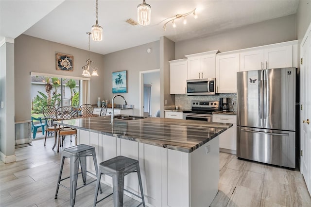 29312 Marker Loop, San Antonio, FL 33576 - kitchen with appliances with stainless steel finishes, backsplash, a center island with sink, white cabinets, and hanging light fixtures