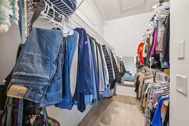 walk in closet featuring attic access and wood finished floors