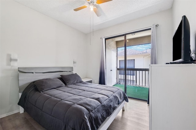 bedroom featuring access to outside, wood finished floors, baseboards, and a textured ceiling