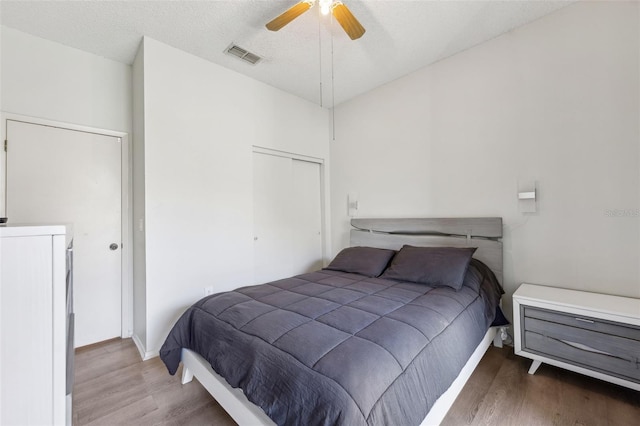 bedroom featuring visible vents, a textured ceiling, a closet, and wood finished floors