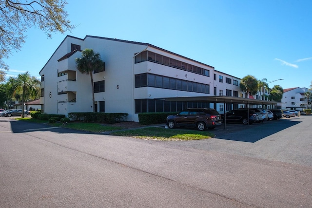 view of building exterior with covered and uncovered parking