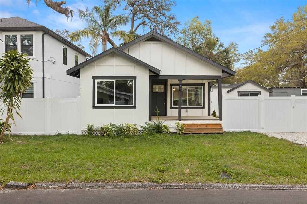 1103 E Louisiana Ave, Tampa, FL 33603 - view of front of property featuring covered porch, fence, board and batten siding, and a front yard
