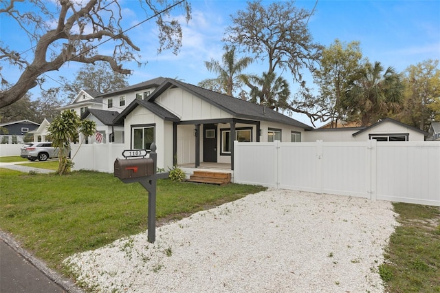 view of front of house with covered porch, a gate, fence, a front lawn, and board and batten siding