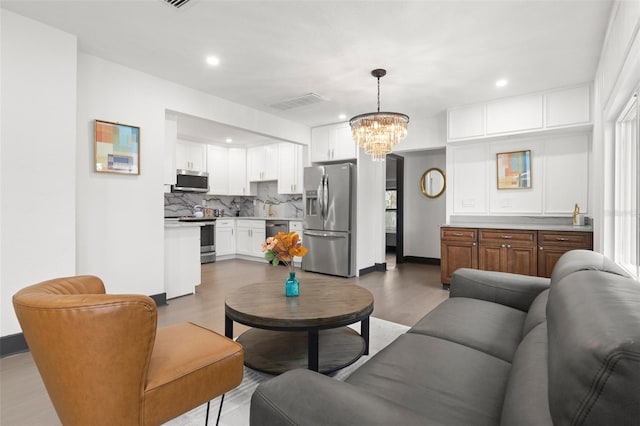 living room with baseboards, visible vents, wood finished floors, a notable chandelier, and recessed lighting