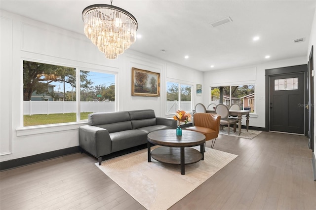 living room featuring recessed lighting, wood-type flooring, baseboards, and an inviting chandelier