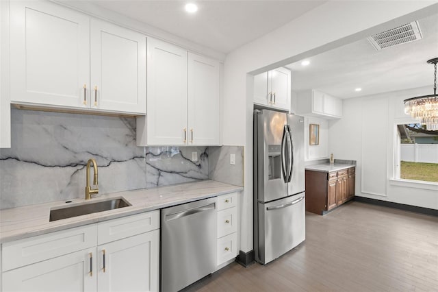 kitchen with stainless steel appliances, visible vents, a sink, and white cabinetry