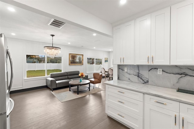 kitchen featuring white cabinets, visible vents, decorative backsplash, and freestanding refrigerator