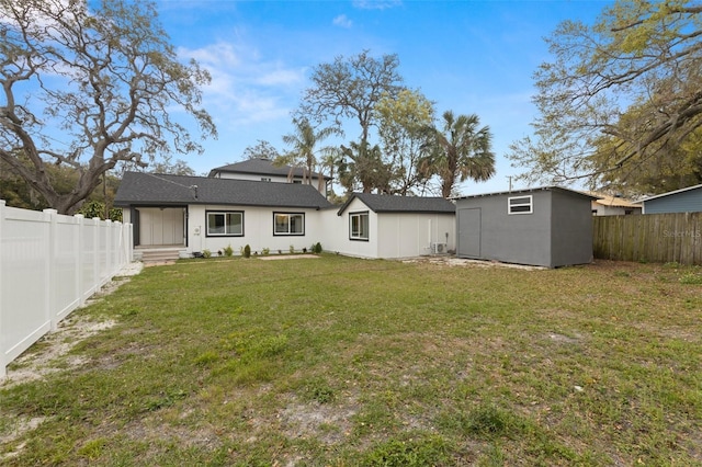 rear view of property featuring a storage shed, a fenced backyard, an outdoor structure, and a yard