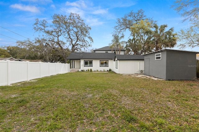 back of house featuring a fenced backyard, an outbuilding, and a yard