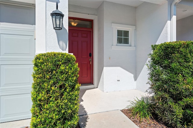 entrance to property featuring a garage and stucco siding