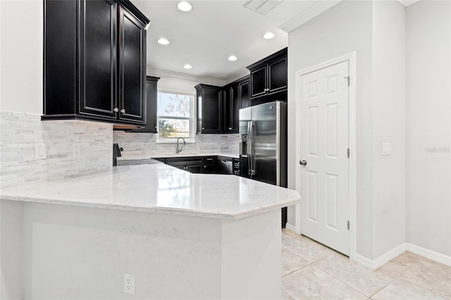 kitchen featuring visible vents, stove, dark cabinetry, stainless steel refrigerator with ice dispenser, and a sink