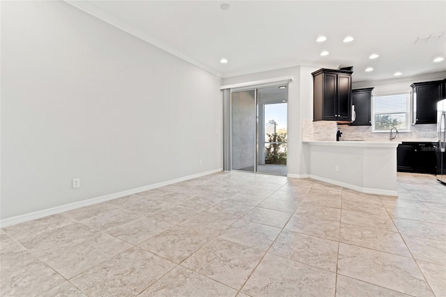 kitchen with tasteful backsplash, ornamental molding, light countertops, and baseboards