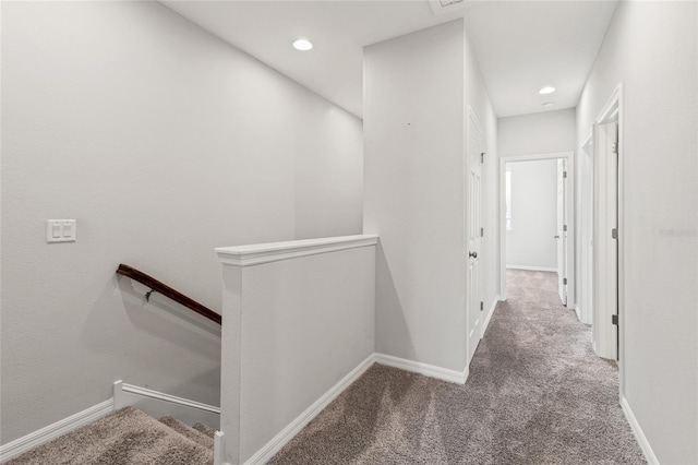 hall with carpet flooring, an upstairs landing, and baseboards