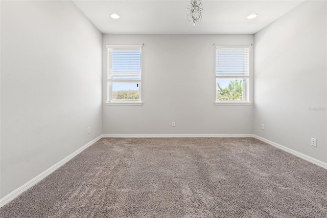 spare room featuring carpet floors, a healthy amount of sunlight, and baseboards