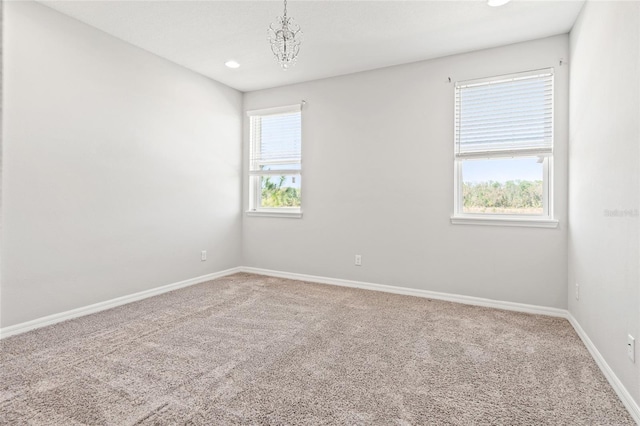 carpeted empty room with recessed lighting, an inviting chandelier, and baseboards