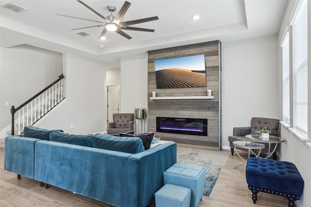 living area featuring a tray ceiling, wood tiled floor, visible vents, and a ceiling fan