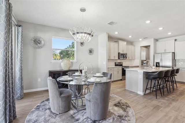 dining space featuring visible vents, baseboards, light wood-type flooring, recessed lighting, and an inviting chandelier