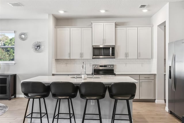 kitchen with light wood-style flooring, tasteful backsplash, visible vents, and appliances with stainless steel finishes