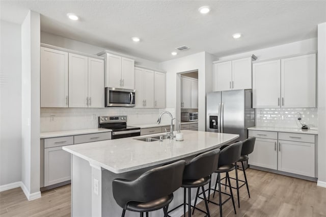 kitchen with a sink, visible vents, a kitchen bar, and stainless steel appliances