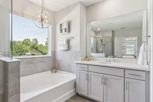 bathroom featuring visible vents, a garden tub, a stall shower, an inviting chandelier, and vanity