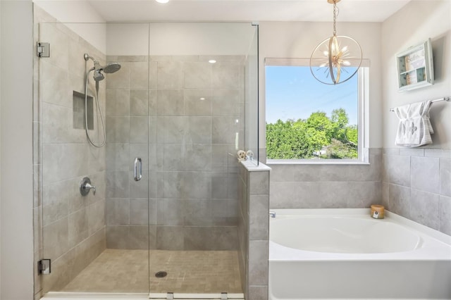 bathroom with a notable chandelier, a bath, and a stall shower