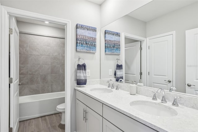 full bath featuring double vanity, toilet, wood finished floors, and a sink