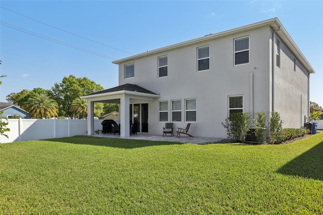 back of property with a patio, a yard, fence, and stucco siding