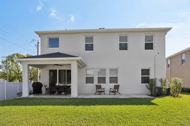 rear view of house with fence, stucco siding, a lawn, a patio area, and a ceiling fan