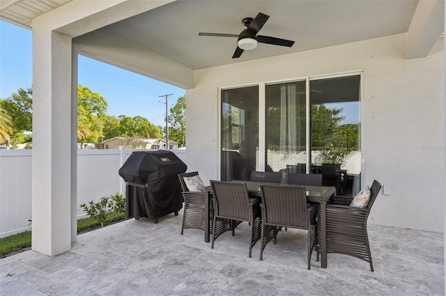 view of patio featuring outdoor dining area, area for grilling, a ceiling fan, and fence