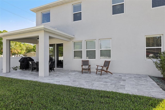 back of house with a lawn, a patio area, fence, and stucco siding