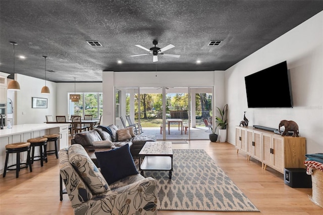 living room with light wood-style floors, visible vents, and a textured ceiling