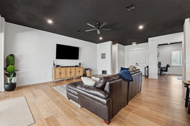 living area with light wood-style floors, visible vents, and ceiling fan