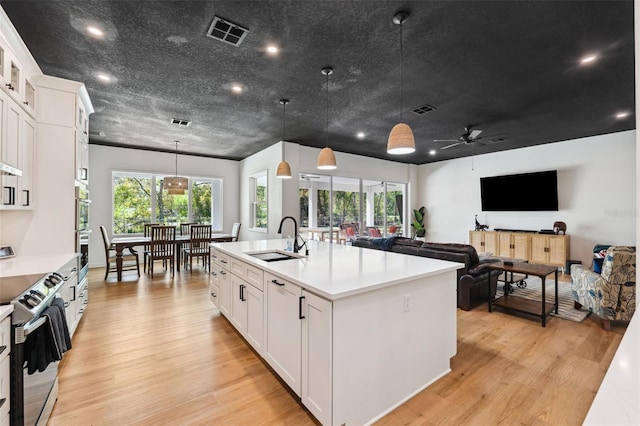 kitchen with light wood finished floors, electric range, visible vents, light countertops, and a sink