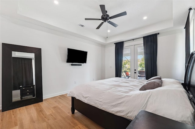 bedroom with visible vents, a raised ceiling, access to exterior, french doors, and light wood-style floors