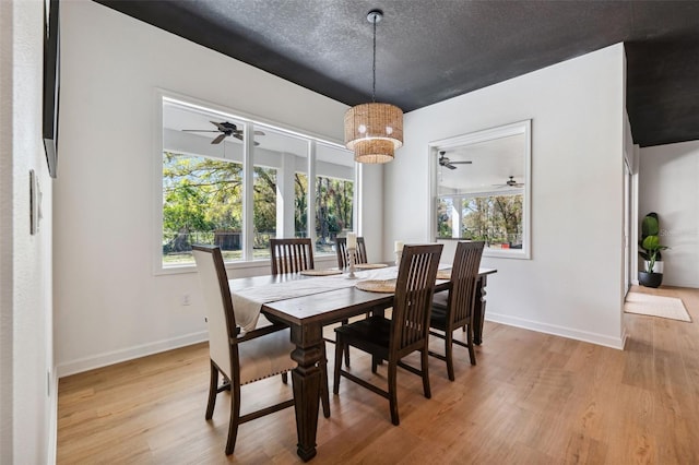 dining room featuring a textured ceiling, ceiling fan, baseboards, and light wood-style floors